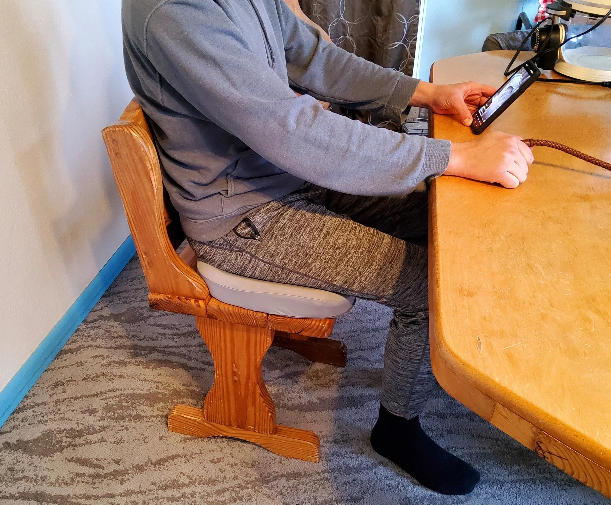 לקוח יושב על כרית iCanSit בבית על ספסל עץ